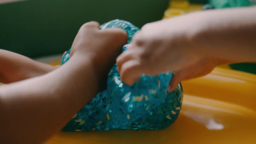 Two children play with blue slime using their hands in a sensory activity