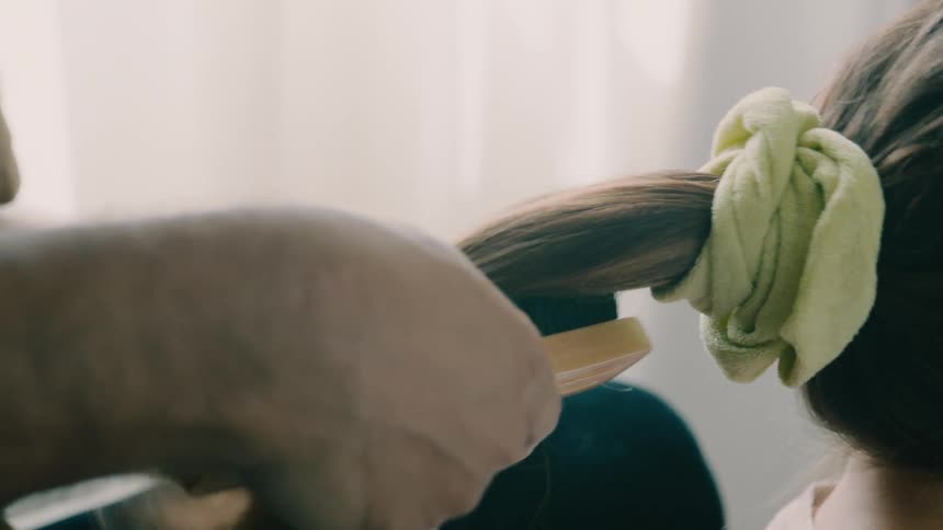 Father brushing his daughters ponytail with a brush
