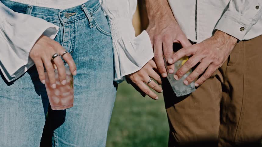 The hand of a couple holding a glass of drink and then they hold hands