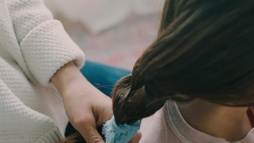 Mother gently adjusts her childs hair braid