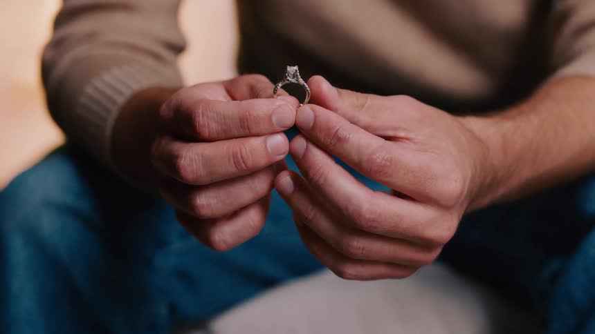 A man moves a diamond ring around in his hands