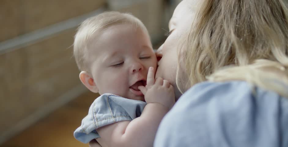 A woman kisses a baby that she is holding