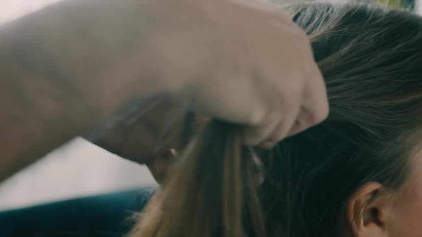 Someones hands are busy braiding another persons dark brown hair