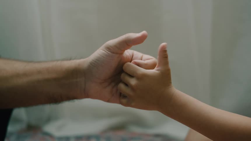Two adults play a thumb war locking hands and laughing as they compete playfully