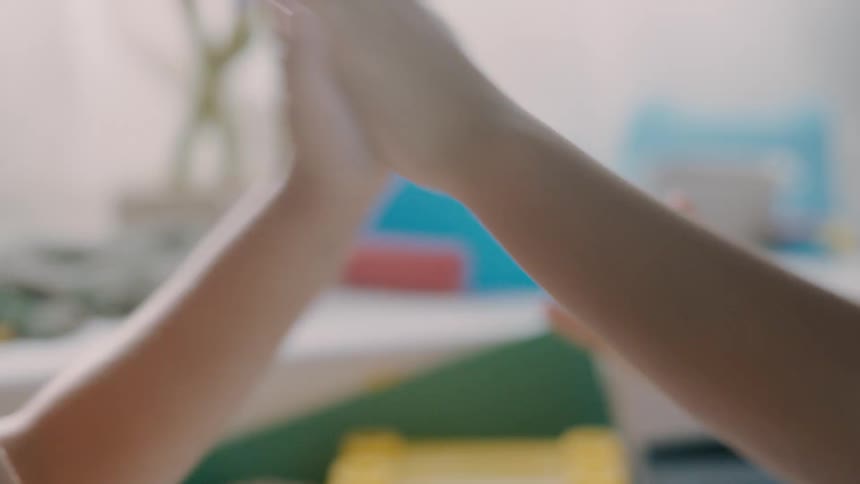 Two girls play a hand clapping game while indoors during the daytime