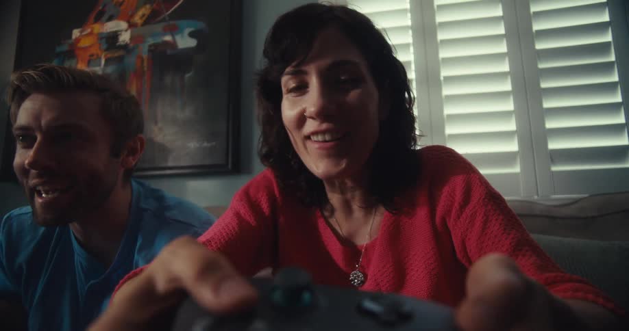 A cheerful couple plays a video game together indoors sharing joy and excitement