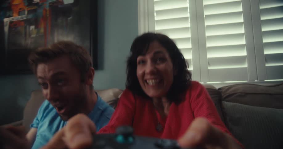 A happy couple excitedly playing video games together indoors at home
