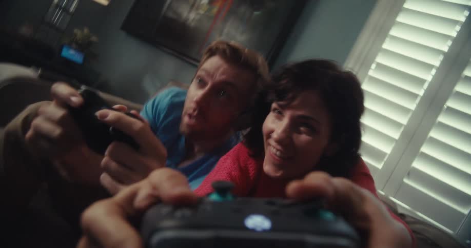 Friends play a video game while sitting on a couch near the window