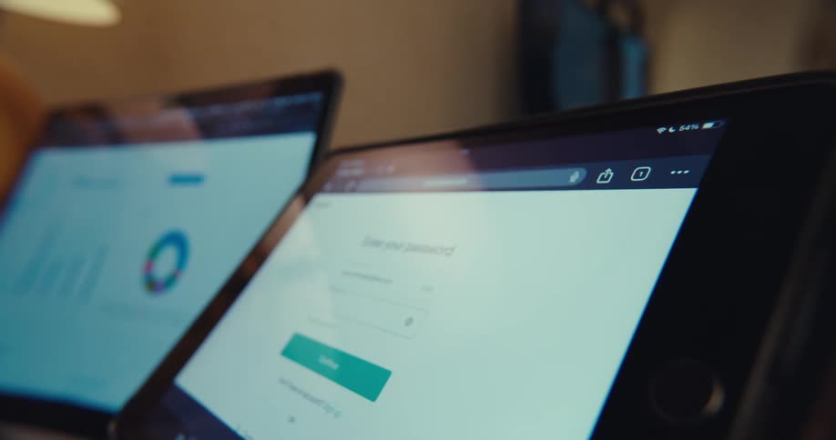 Close up of screens of a tablet and laptop displaying an application sign in page and a chart diagram respectively
