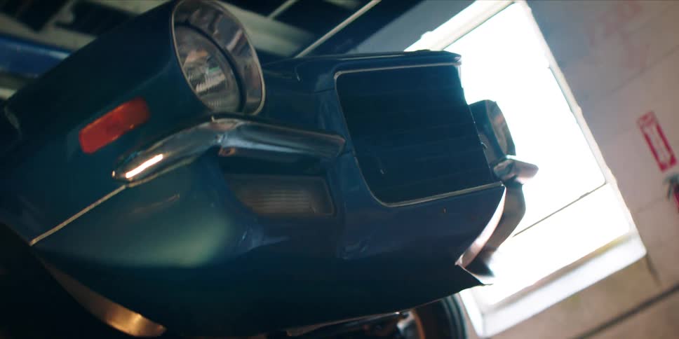 Close up of the front view of a blue car suspended in the air in a workshop