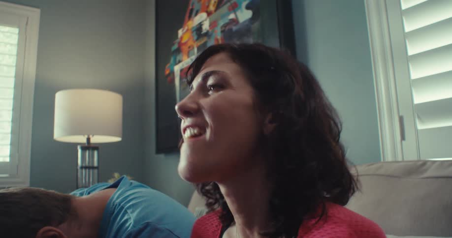 Couple celebrate happily at intervals as they compete while playing video games with controllers in a living room