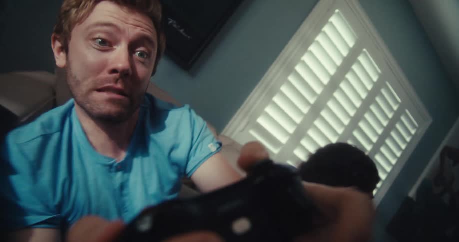 Man and woman compete and tilt side to side while gaming on a couch in a living room
