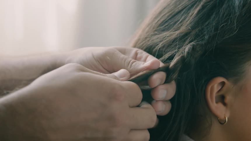 A father braids his daughters hair