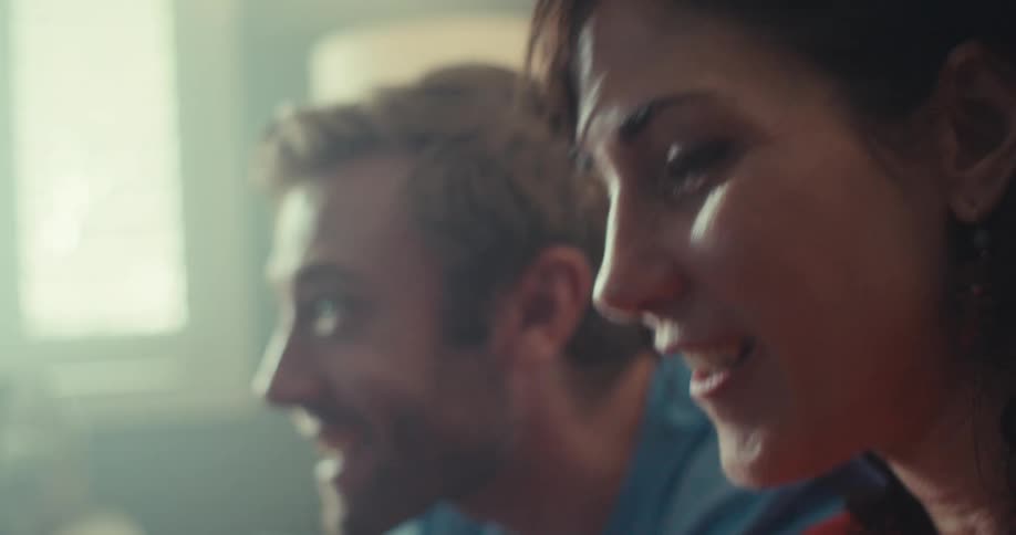 A woman and man are playing a video game and celebrating