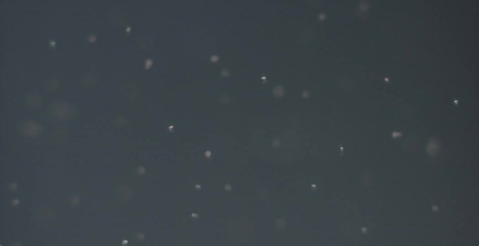 White particles floating in a gray room