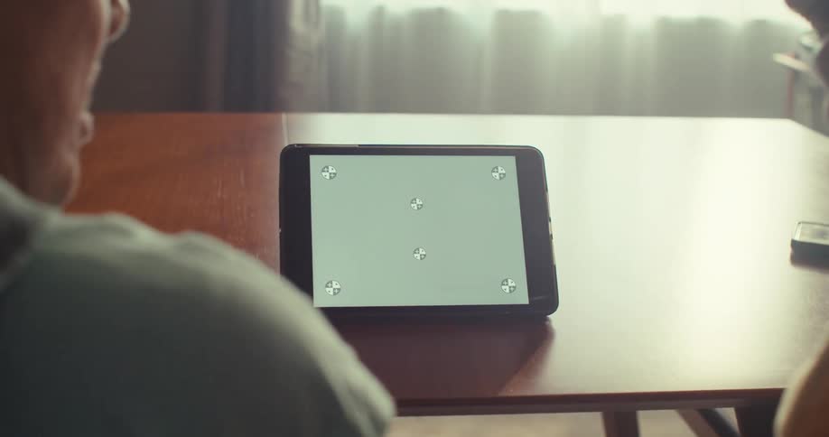 Elderly couple sitting indoors engaged in conversation while looking at a tablet