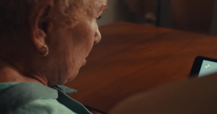 Elderly couple sits at their dining room table while concentrating on a tablet screen
