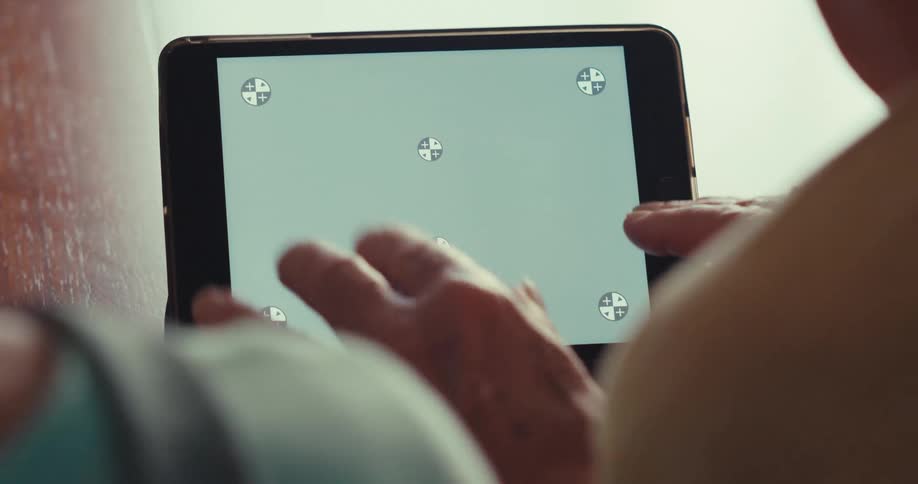 Two people wave at the screen of the tablet