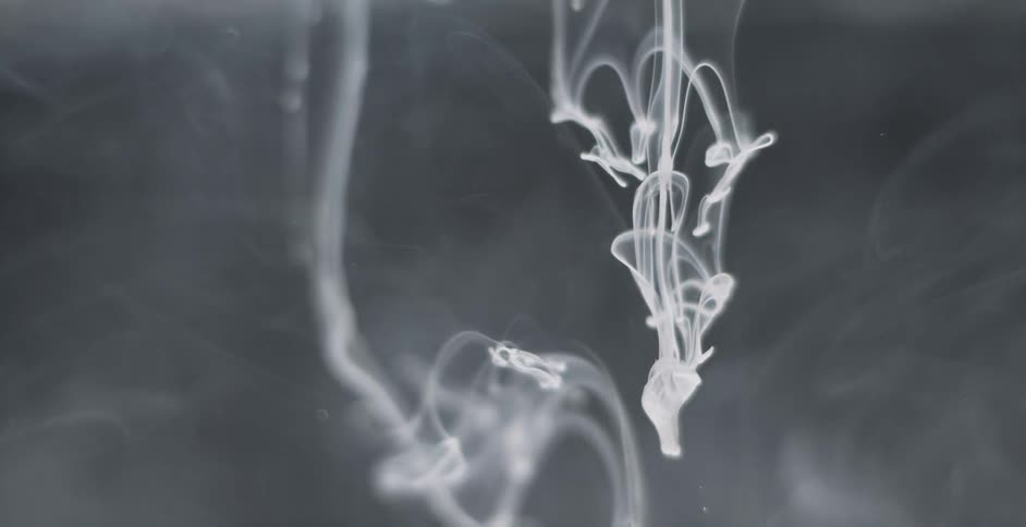 White substance falls and flows into clear liquid