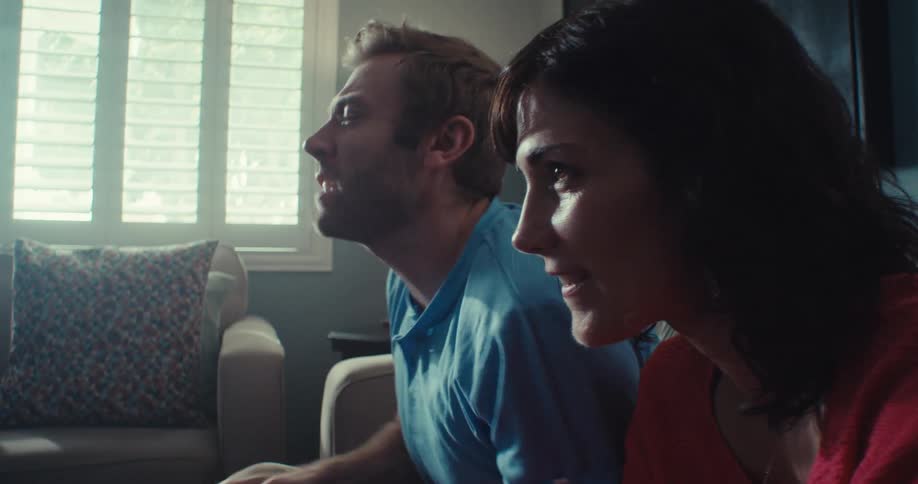 A cheerful couple indoors competes in a video game with the wife celebrating her win