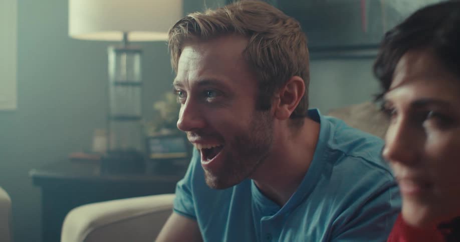 Man and woman play a video game while sitting on their couch