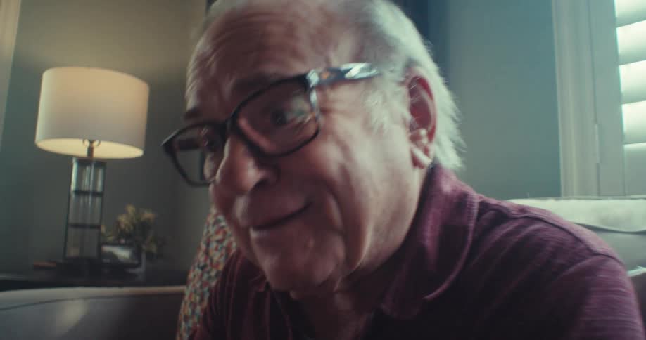An old man smiles during a happy video call on his smartphone indoors