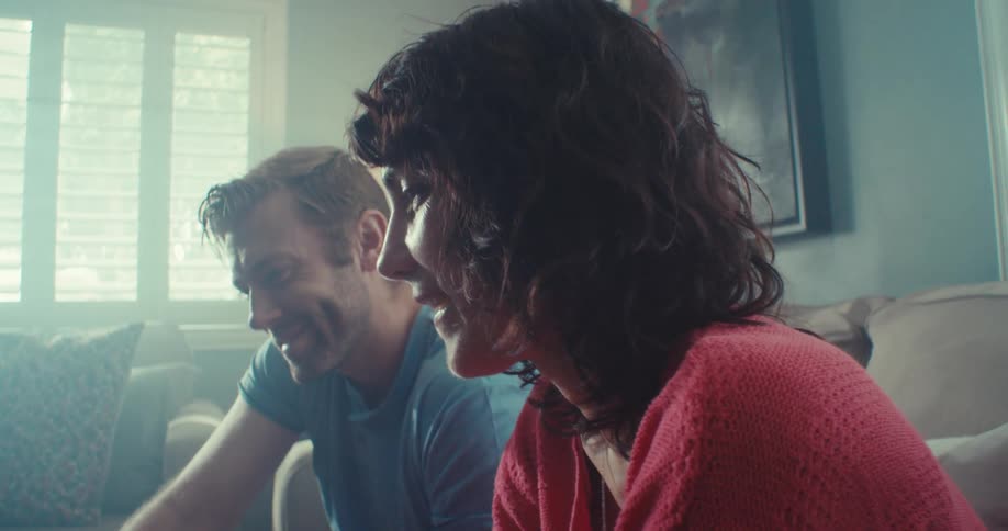 A man and woman are smiling and talking while sitting together in a cozy living room