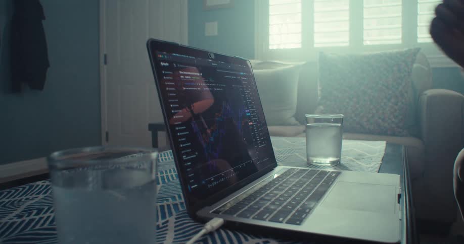 Man sitting in the living room gestures at the screen of the laptop on the coffee table