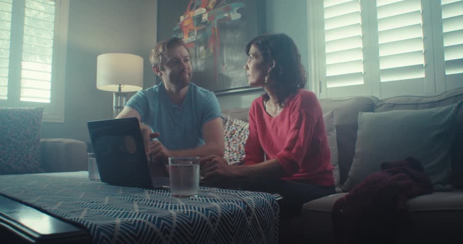 A man and woman talk together by the laptop