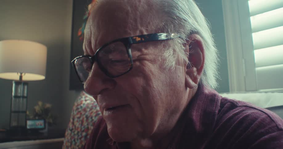 The face of an elderly man who is using a cell phone and has a subtle smile