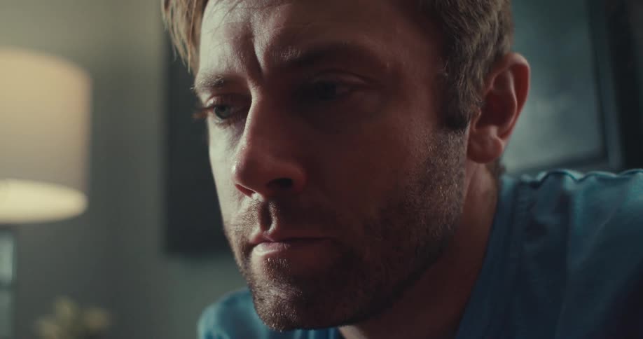 A man in a living room thoughtful and serious
