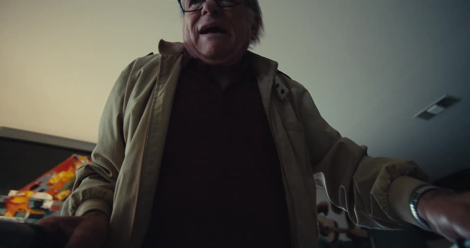 Elderly man leans forward distressed gripping a walker indoors