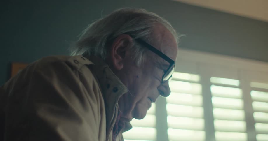 A man enters the home and slowly moves to sit down