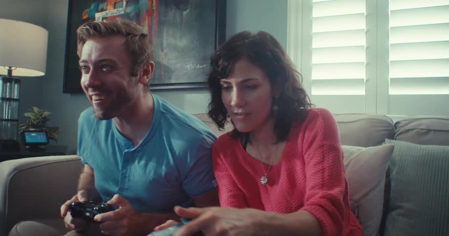 Happy couple excitedly plays a video game at home competing with joy and laughter