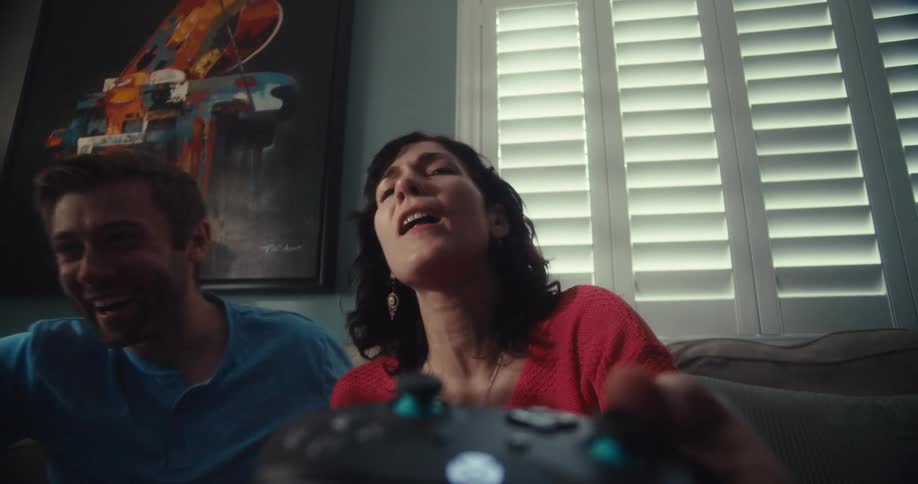 Woman holding video game remote control feeling dissatisfied and her friend next to her cheering happily