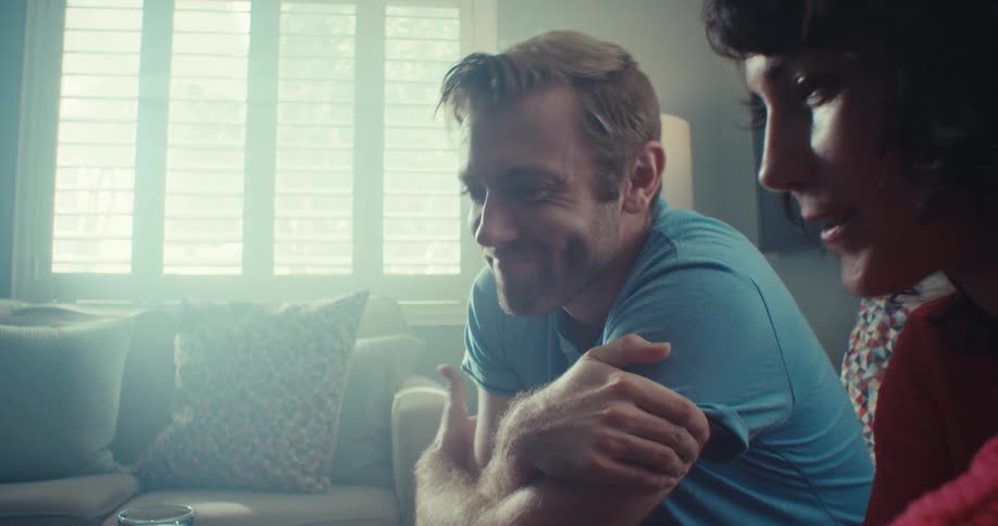 Man and woman share a warm smiling moment on a sunlit couch