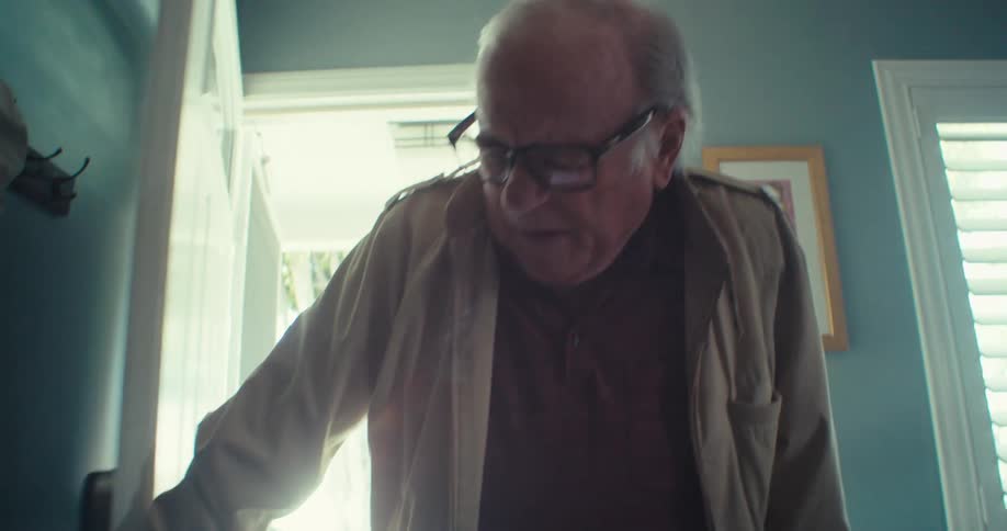 An elderly man carefully enters a house using a walker as he deliberately closes the door behind him