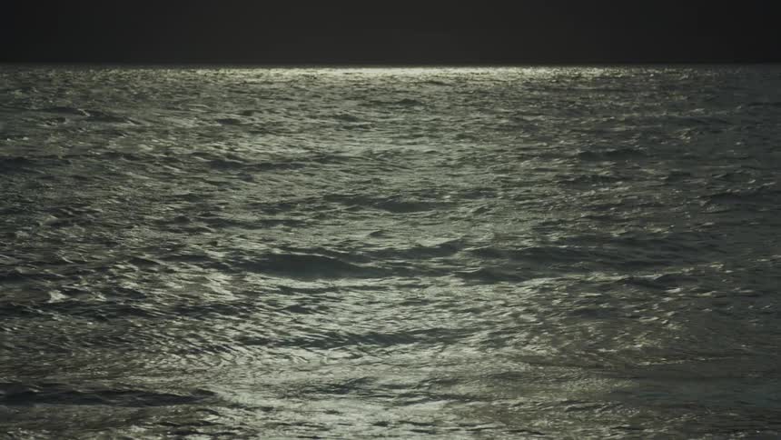 An ocean view with waves rolling toward the shore at sunset