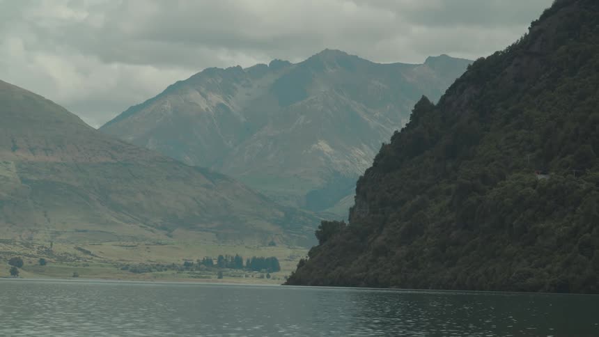 Water flows past foggy mountains under an overcast sky