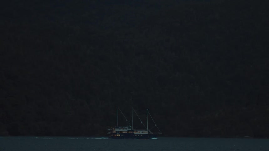 A boat gliding across a lake during the evening with calm waters reflecting the fading light of dusk