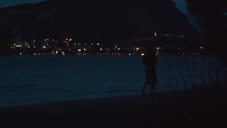 A woman walks on the beach at sunset