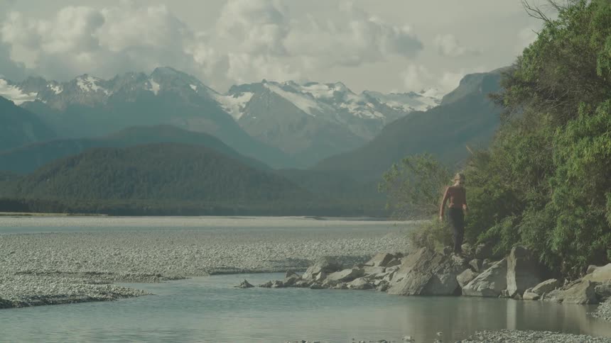 A woman is hiking on the rocks by the lake