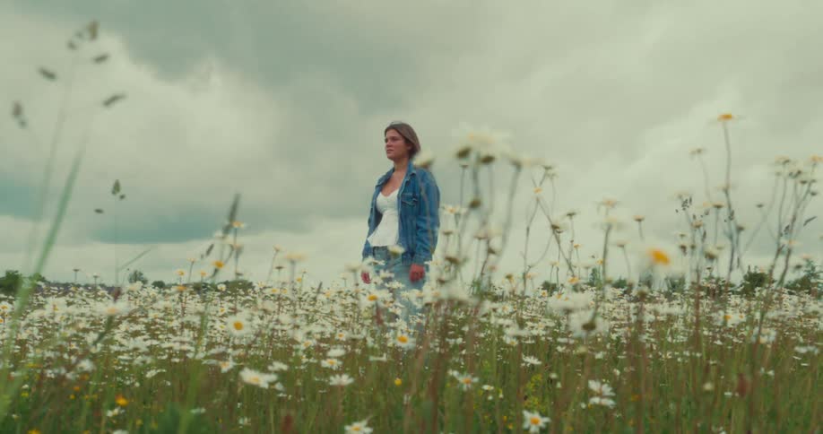 Woman in denim jacket in a field of daisies