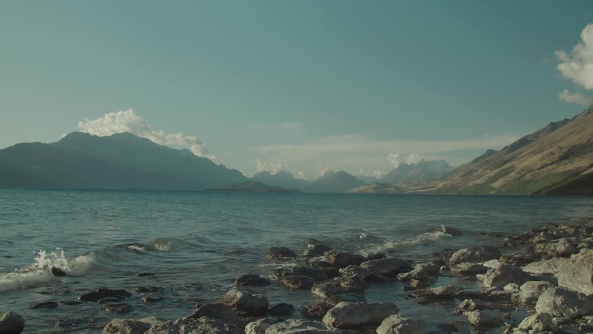 A scenic coastal landscape showing mountains rocky beach sand and sky