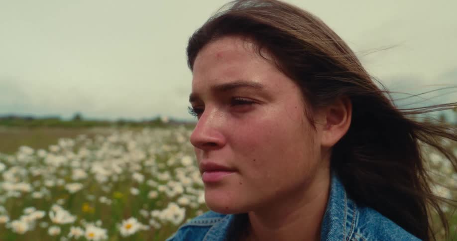Womans profile against a field of swaying daisies in the wind