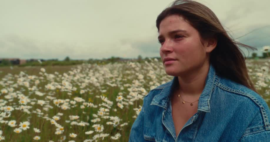 A womans hair blows in the wind in a field of flowers