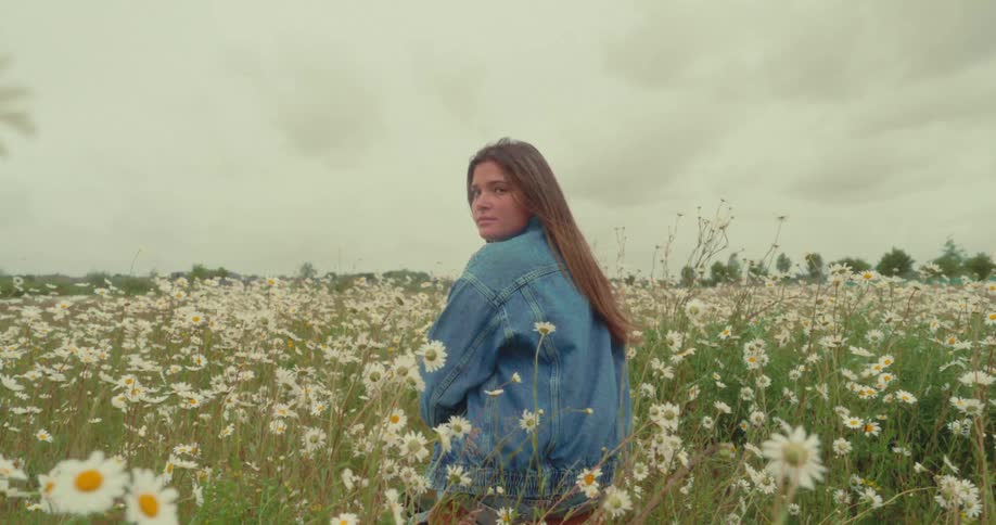 A woman turns around while sitting in the grass