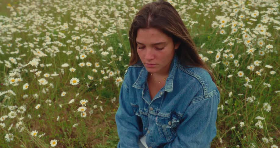 A woman sits peacefully in a flowerfilled yard surrounded by nature