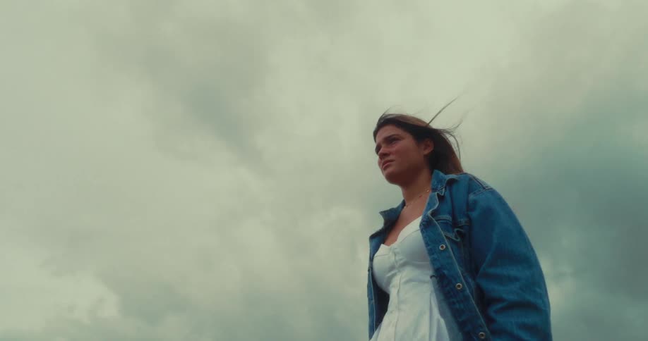 A girl is standing outside on a windy day