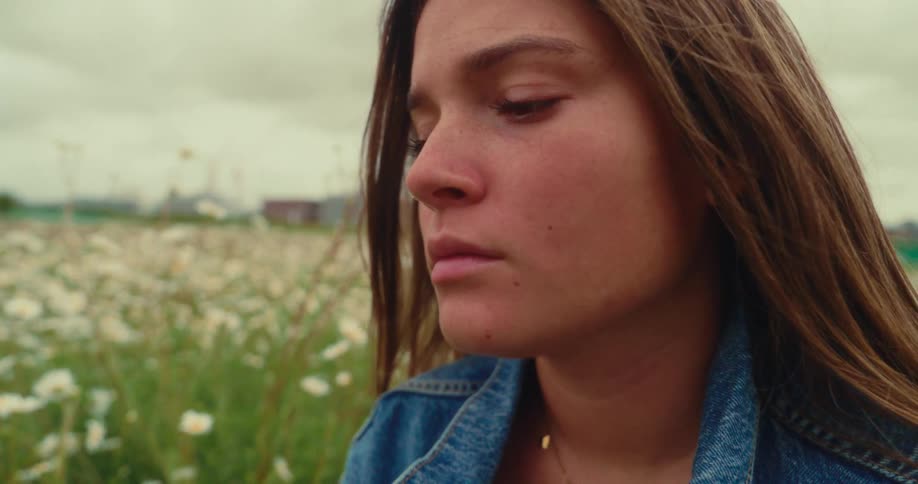 A young woman in a closeup shot with a field of flowers in the background